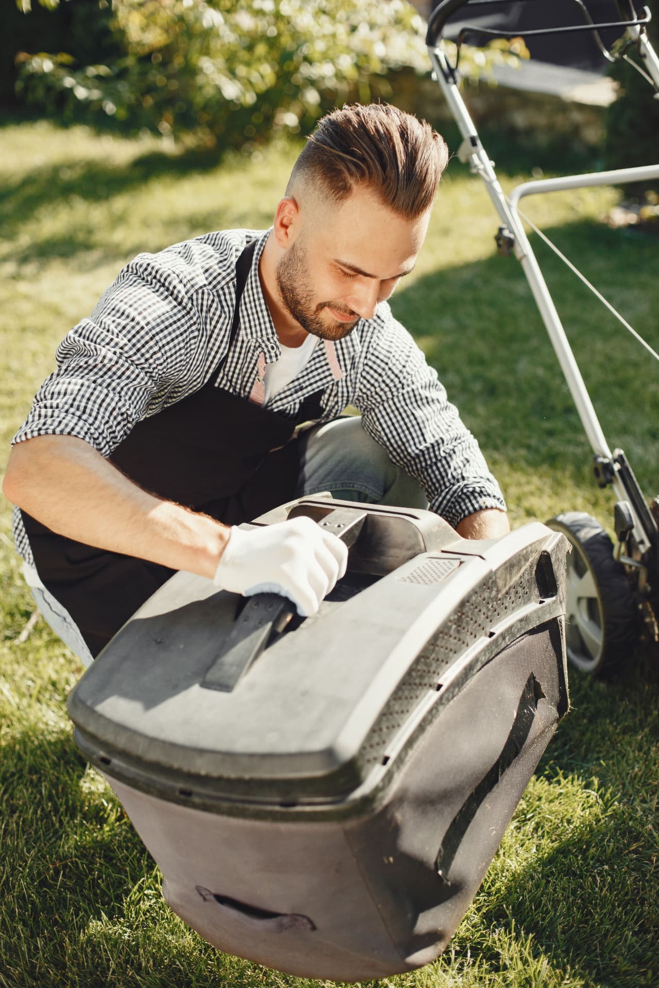 Lawn care worker checking a mower in a backyard